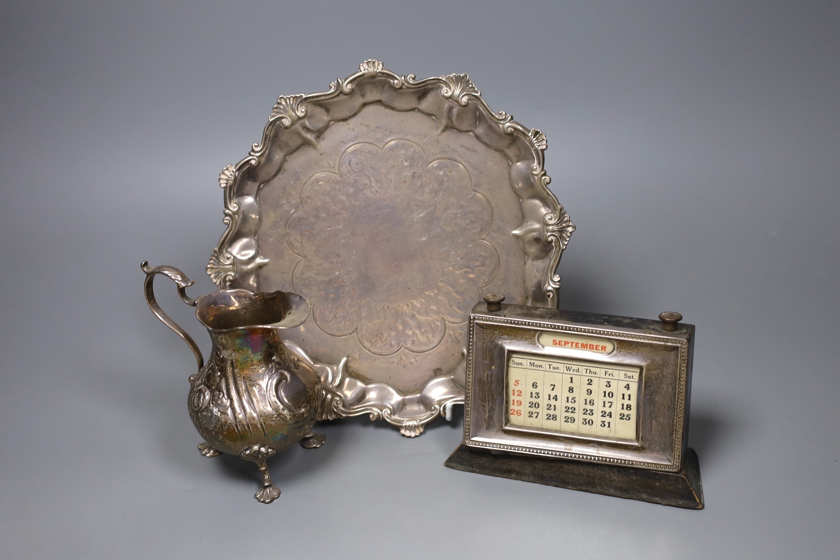 A Victorian silver waiter with scroll and piecrust border, London 1860, 23cm, 13 oz, a Victorian silver cream jug, 4.5oz and a later silver mounted desk calendar
